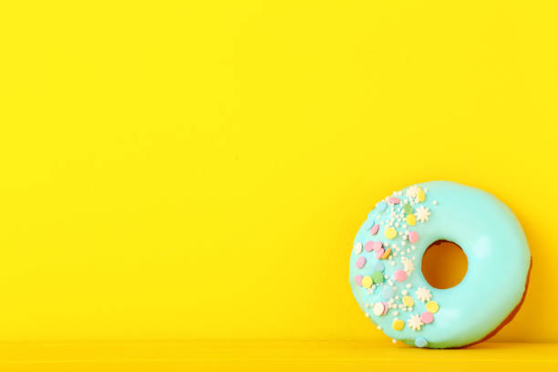 istock Tasty donut with sprinkles on yellow background 982364970