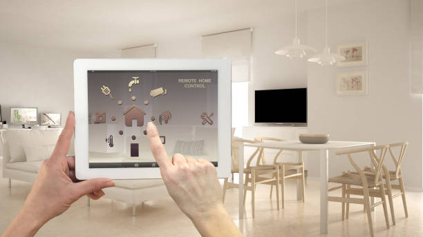 istock Smart remote home control system on a digital tablet. Device with app icons. Minimalist modern bright living room in the background, architecture interior design 982365168