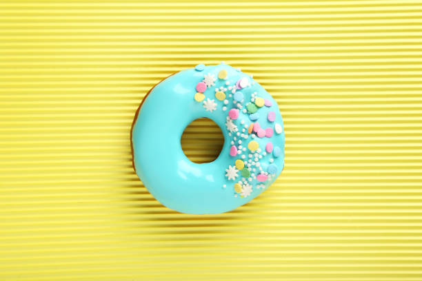 istock Tasty donut with sprinkles on paper background 982365718