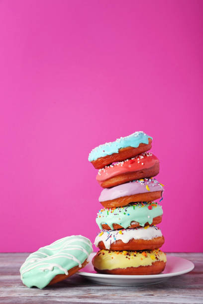 istock Tasty donuts with sprinkles in plate on wooden table 982368216