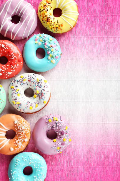 istock Tasty donuts with sprinkles on paper background 982369340