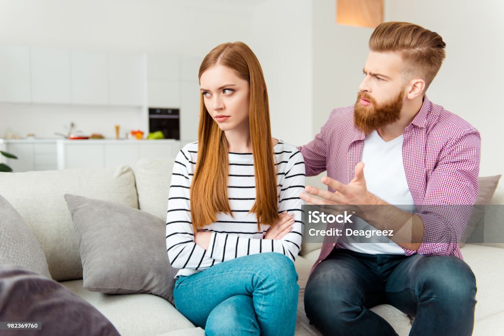 Misunderstanding people person concept. Puzzled annoyed handsome irritated boyfriend trying to figure out the reason of resentment. Pretty girl doesn't want to listen to boyfriend sitting crossed arms Displeased Stock Photo