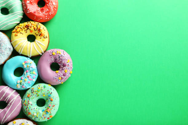 istock Tasty donuts with sprinkles on paper background 982373594