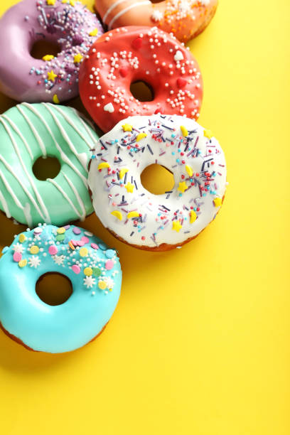 istock Tasty donuts with sprinkles on yellow background 982374158