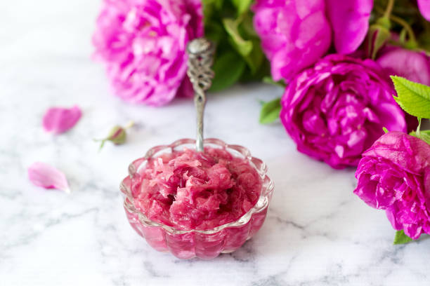 Jam with rose petals in a glass bowl and bright roses on a light background. Jam with rose petals in a glass bowl and bright roses on a light background. Selective focus. bud candy stock pictures, royalty-free photos & images