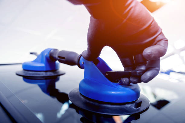 istock Automobile special workers replacing windscreen or windshield of a car in auto service station garage. 982383886