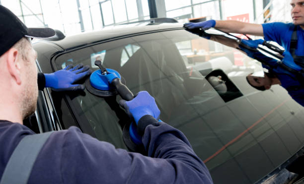 automobile special workers replacing windscreen or windshield of a car in auto service station garage. - windshield imagens e fotografias de stock