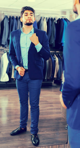 istock Young man is trying on jacket in front of the mirror 982388898