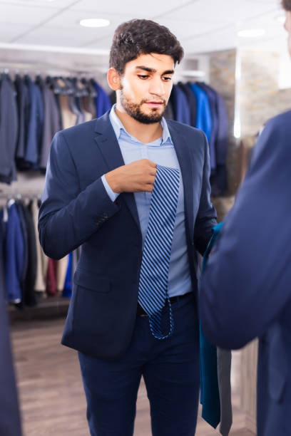 istock Shopper is picking up tie for jacket in front of the mirror 982388982