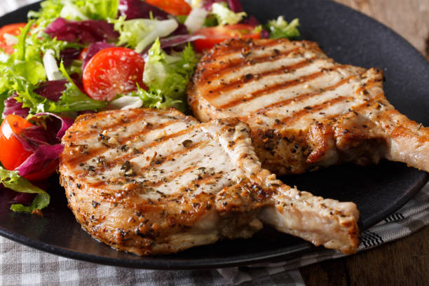 gegrild varkensvlees steak met bot en frisse salade close-up. horizontale - karbonade stockfoto's en -beelden