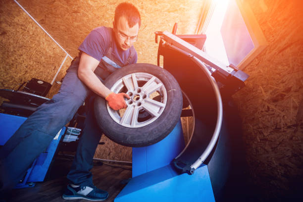 istock Professional car mechanic replace tire on wheel. 982415220