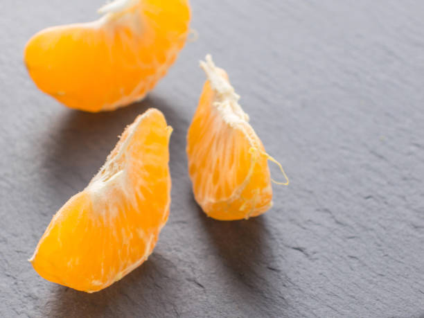 istock Tangerines slices on black background. Orange mandarin 982419050
