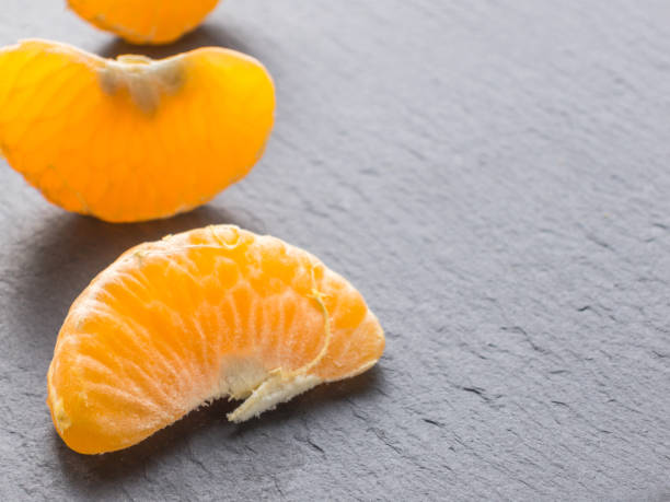 istock Tangerines slices on black background. Orange mandarin 982419124