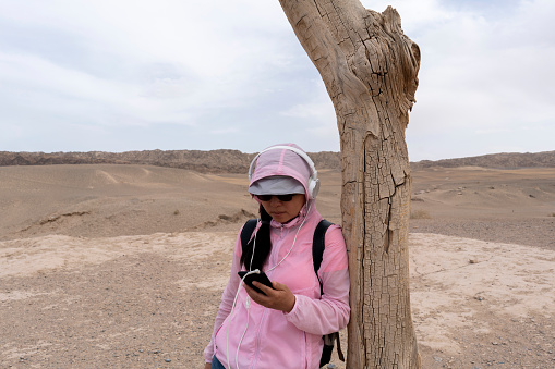 girl listening music under wilt tree on gobi desert