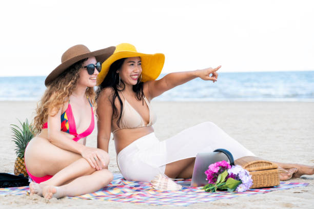 istock Happy women sitting on sand beach in summer. 982444022