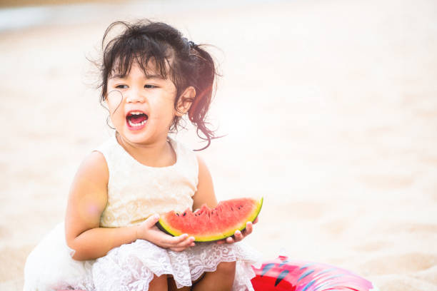 istock Adorable kid eating watermelon on the beach. 982444056