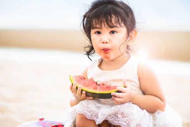 istock Adorable kid eating watermelon on the beach. 982444080
