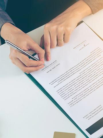 Businesswoman signs agreement contract at the office. Close up shot at the woman's hand. Concept of business partnership and legal activities of lawyer.