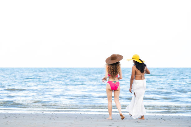 istock Happy women go sunbathing at sand beach in summer. 982444172