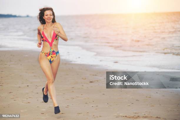 Attractive Woman Runs On Sand Beach In Summer Stock Photo - Download Image Now - Marathon, Running, Triathlon