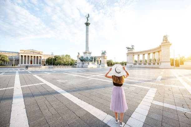 Heroes square with young woman tourist standing back during the morning light in Budapest city, Hungary