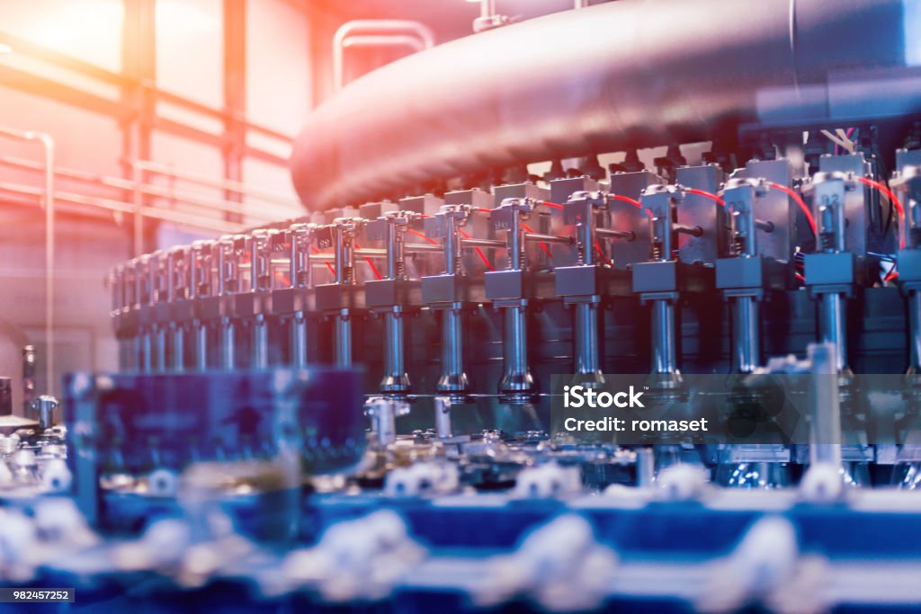 Automatic filling machine pours water into plastic PET bottles. Brewing production. Automatic filling machine pours water into plastic PET bottles. Brewing production. Industrial background. Manufacturing Stock Photo