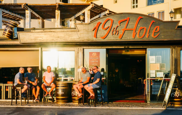 expatriados e turistas britânicos relaxar com bebidas e conversa no terraço de um pub intitulado buraco 19. algarve é um destino de golfe popular - 19th hole - fotografias e filmes do acervo