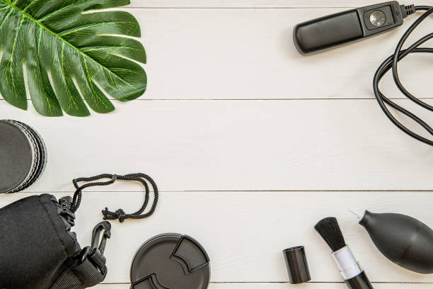 istock photographer working place with lens cover, black lens, case, cleaning tools, remote control and tropical leaf flat lay top view 982481208