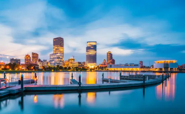 Photo of milwaukee skyline at night with reflection in lake michigan.