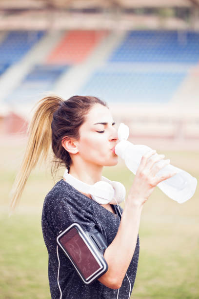 istock Young sportive woman drinking water in a stadium. 982498556