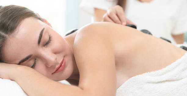 istock Hot stone massage treatment by therapist in spa. 982513970