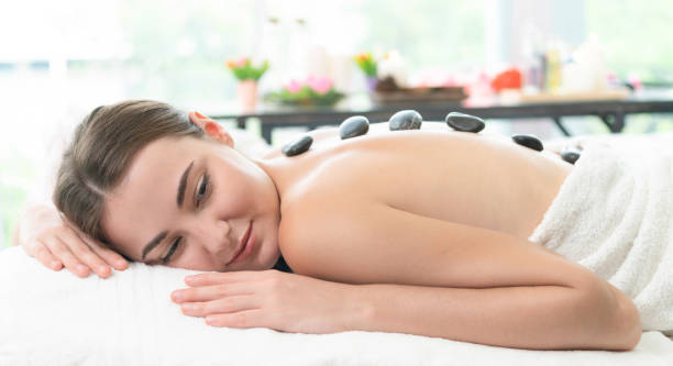 istock Hot stone massage treatment by therapist in spa. 982514042