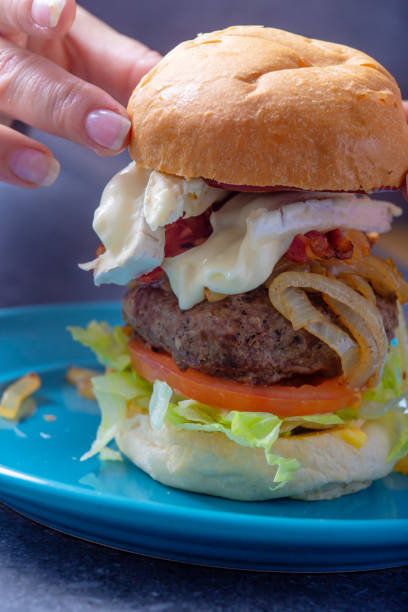 istock A bread bun is placed onto a  delicious cheese and bacon burger 982514994