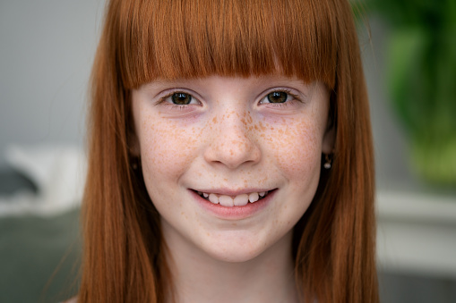 Close-up of face happy little ginger girl with freckles smiling