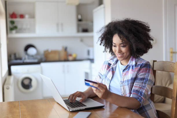 istock African woman using cedit card and laptop at home 982520184