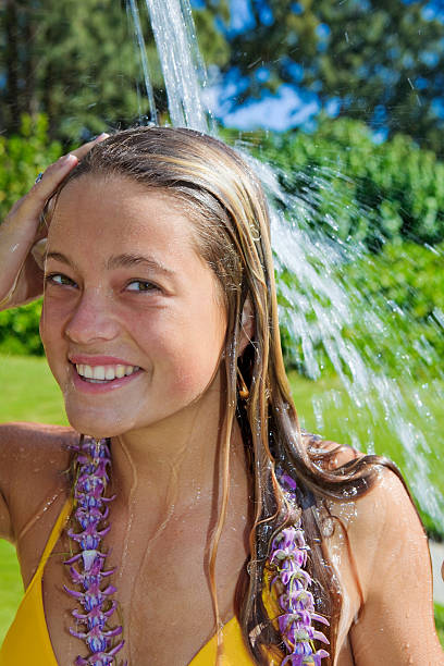 adolescent en bikini jaune prenant une douche en plein air - vertical single flower women teenager photos et images de collection