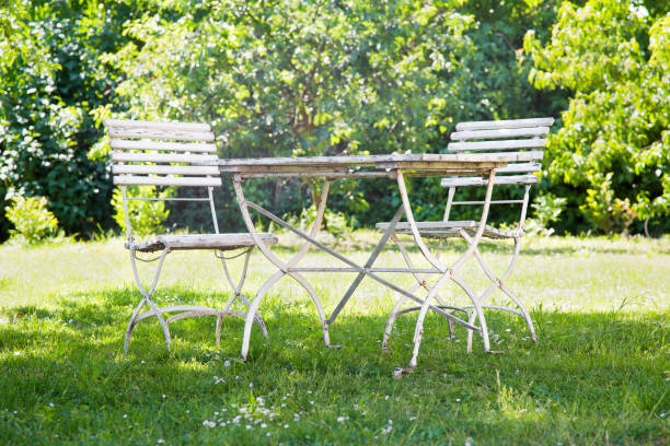istock Rustic old wooden table and chairs standing in the shadow in garden under the trees. 982549302