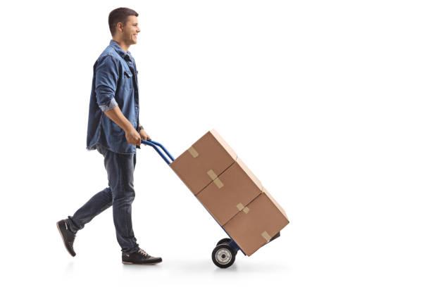 istock Young man pushing a hand truck with boxes 982550006