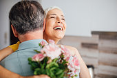 Happy woman holding a bouquet of roses and hugging a man
