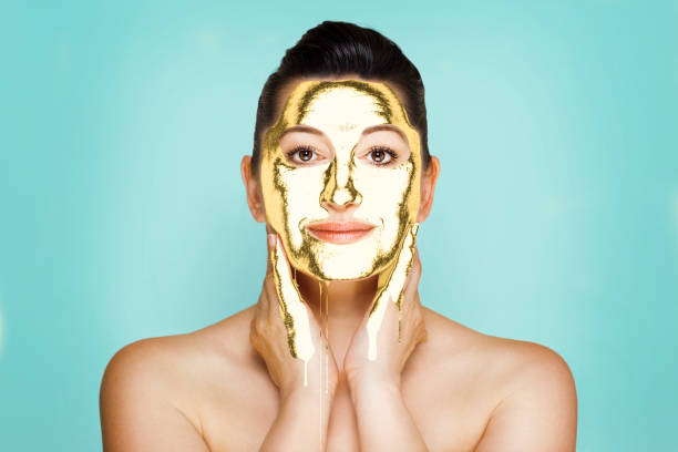 Healthcare time. Upper view of happy modern female in spa salon with golden cosmetic mask on face laying on massage table.