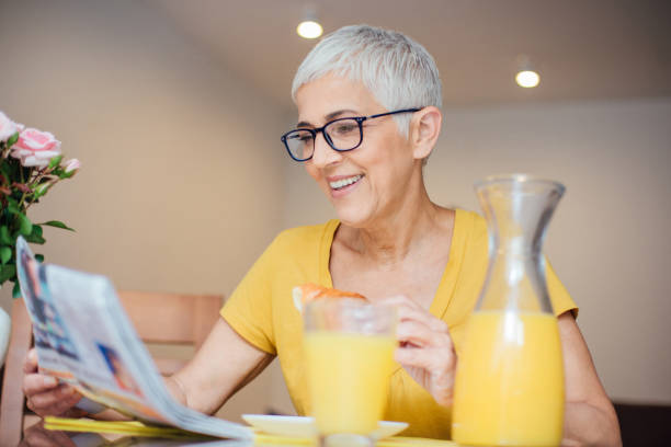 istock Woman wearing eyeglasses reading newspapers over a breakfast 982560654