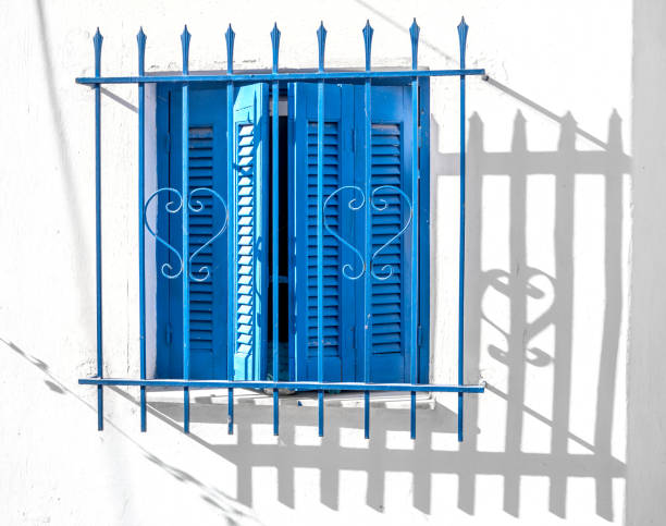 istock Blue window wooden shutters on white wall, Greece 982568468