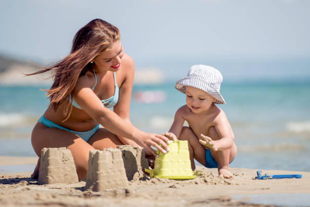 istock Mother and kid making castles of sand on tropical beach 982573560
