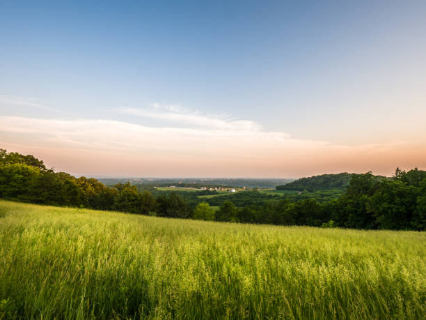 Beautiful panoramic view looking down to the historic city of Galena in Illinois from the top of Horseshoe Mound with long green grass meadow in the foreground and pink and blue sky beyond at sunrise. Beautiful panoramic view looking down to the historic city of Galena in Illinois from the top of Horseshoe Mound with long green grass meadow in the foreground and pink and blue sky beyond at sunrise. illinois stock pictures, royalty-free photos & images