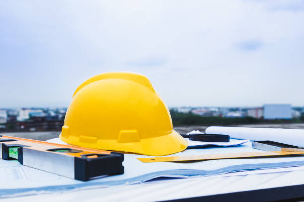 istock Engineer constrction safety helmet and other tools on top of building blueprint outside at construction site, good for construction or building theme background 982573904