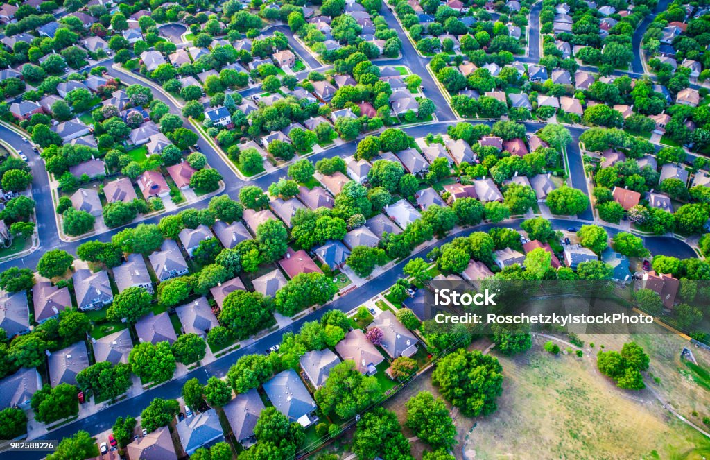 Vast Homes and Thousands of Houses Modern Suburb Development curves layout Vast Homes and Thousands of Houses Modern Suburb Development , green boxes of colorful houses below in a curved modern layout and design aerial drone view from high above suburbia Residential Building Stock Photo