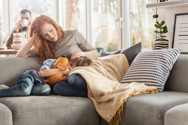 Mother taking care of child Mother taking care of sleepy child while sitting on couch in the living room desease stock pictures, royalty-free photos & images