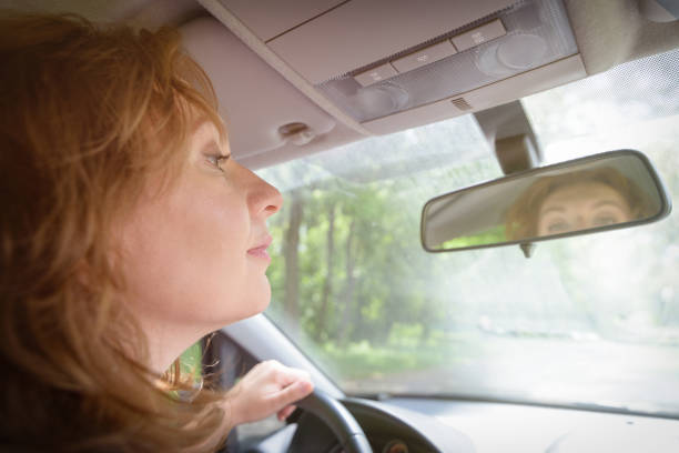istock Woman looking at the mirror in her car 982598648