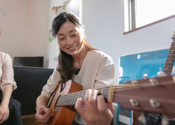 istock Woman playing the guiter at home party 982600268