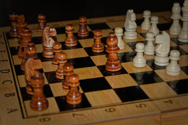 istock Wooden material chess board and chess pieces in low light 982608806